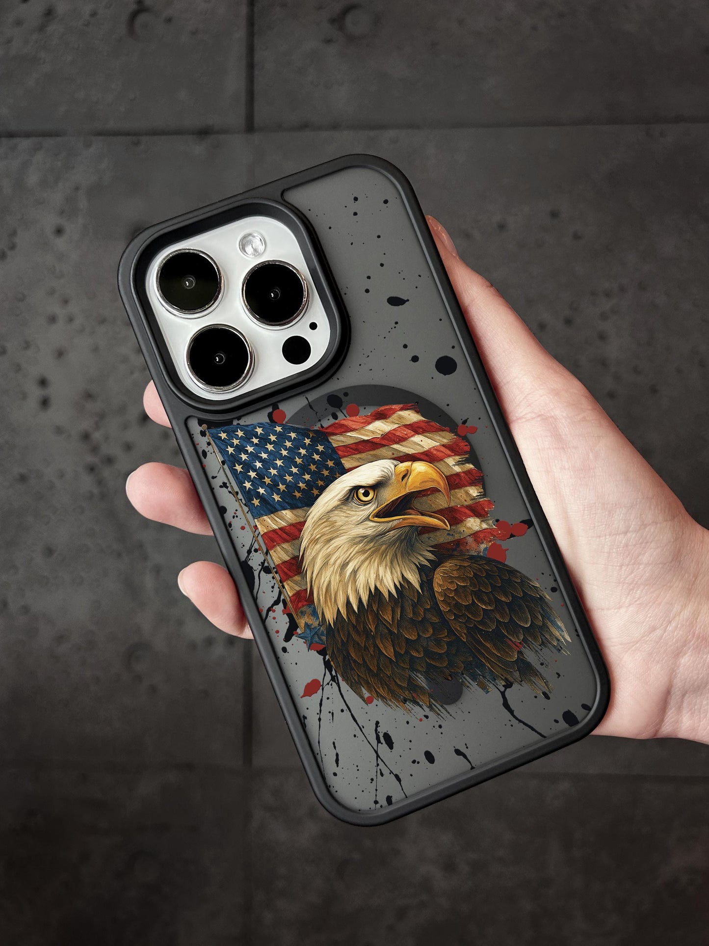 A person&#39;s hand holding a phone case with an image of an eagle and an American flag printed on it.