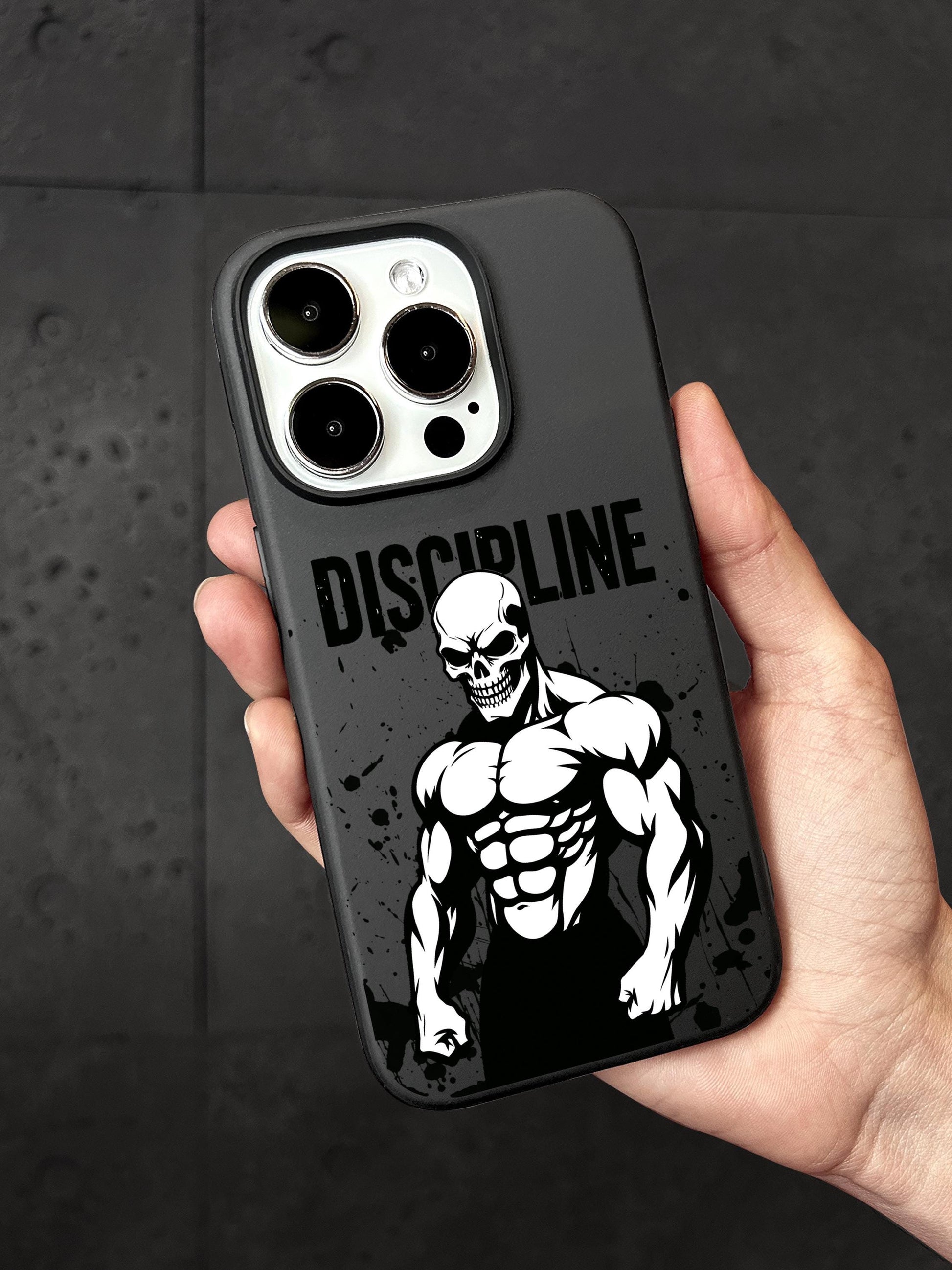 A person&#39;s hand holding a black phone case with a skull design and the word &quot;DISCIPLINE&quot; printed on it.
