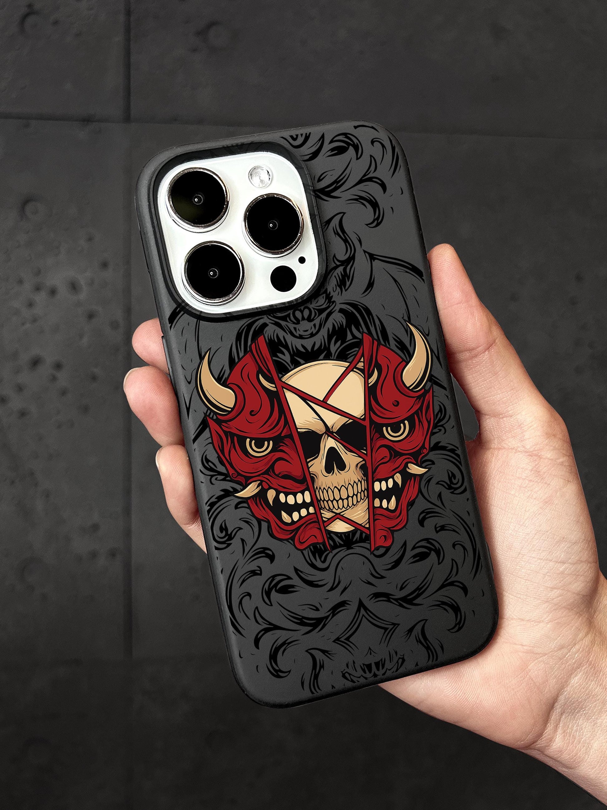 a hand holding a phone case with a skull and devil on it