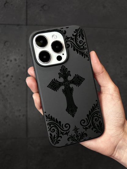 A person&#39;s hand holding a black phone case with a black cross design on it.