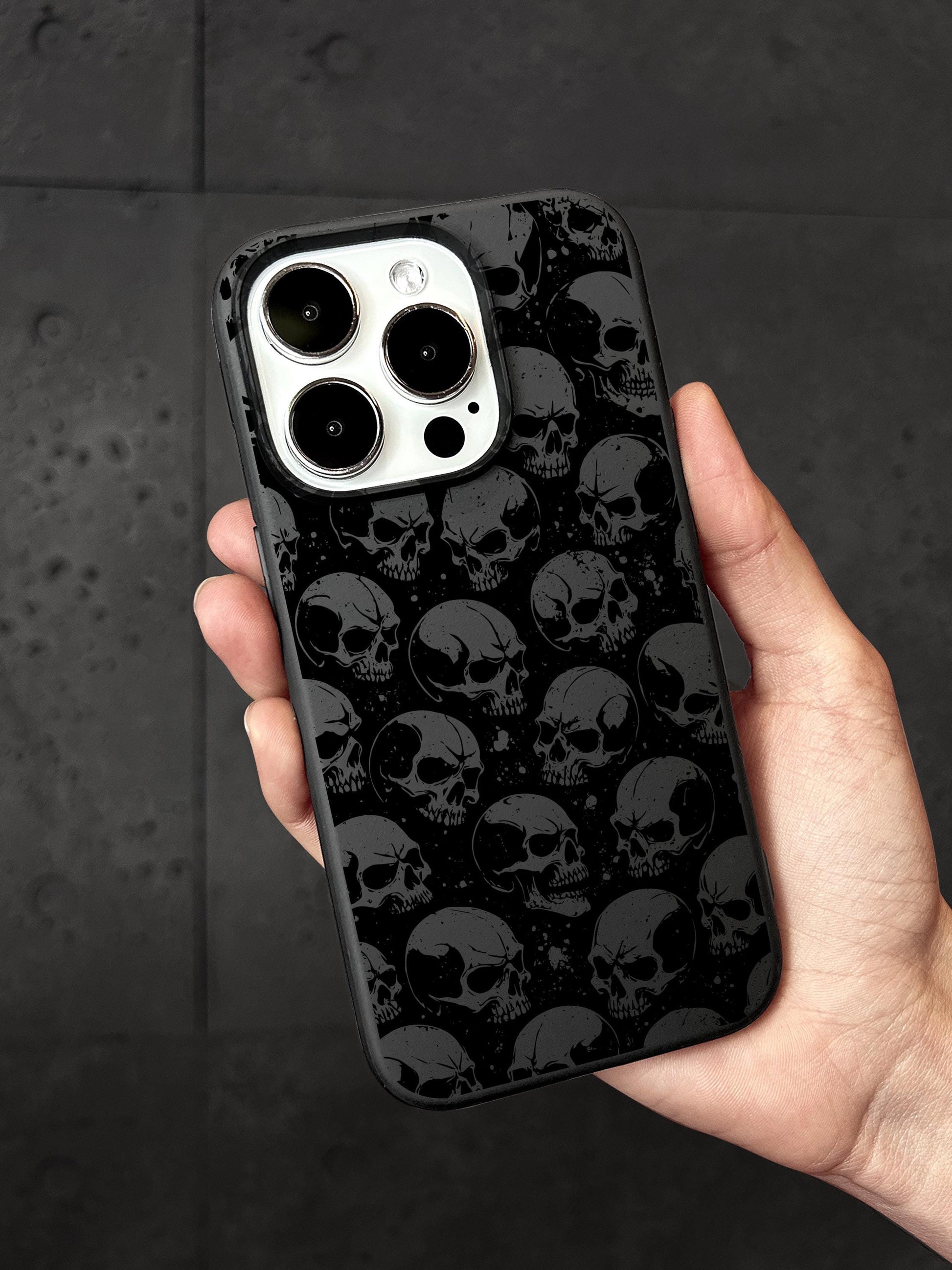 a hand holding a black and white iphone case with skulls on it