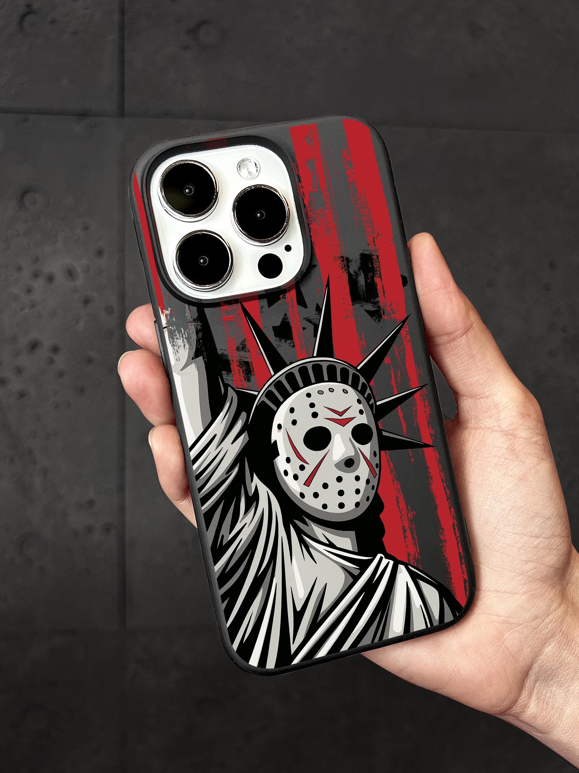 A person is holding a phone case featuring a graphic design of the Statue of Liberty with a mask on it.