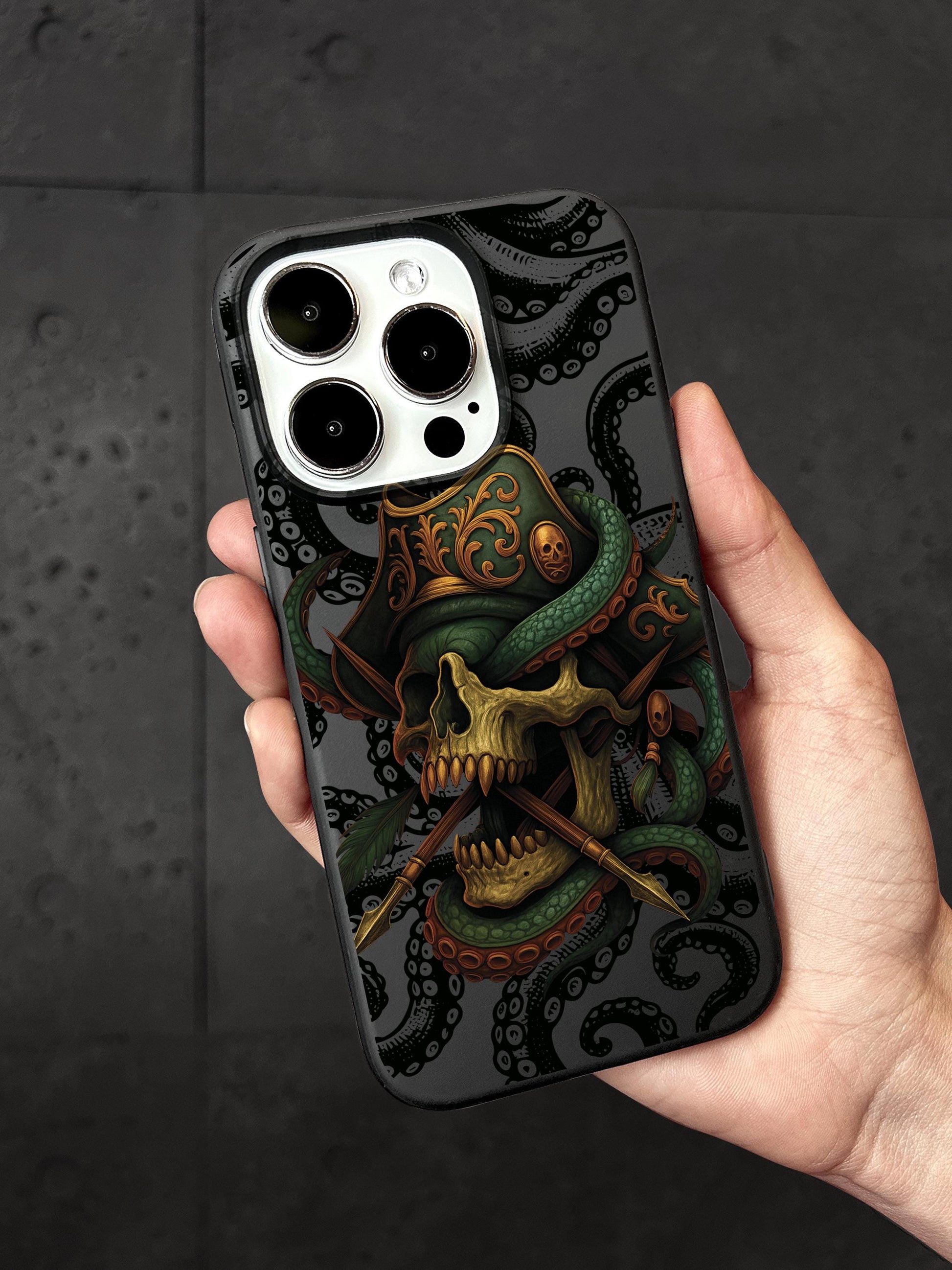A person is holding a phone case with a skull design and an octopus pattern.