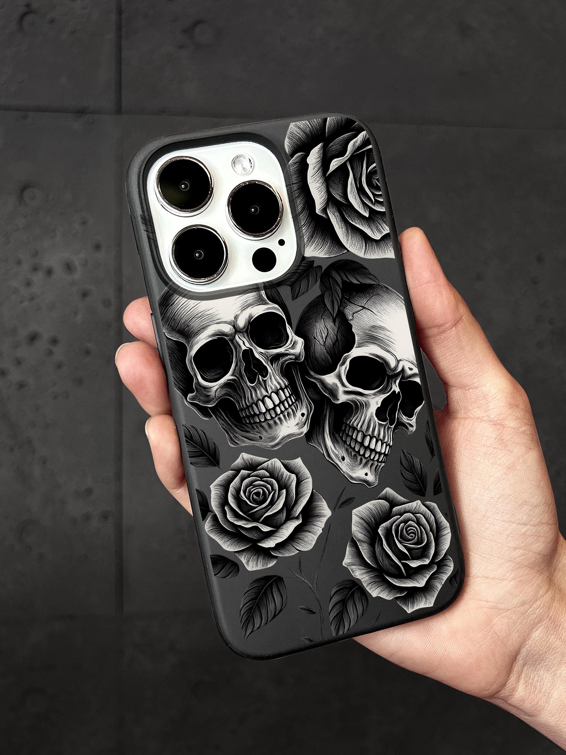 a person holding a phone case with skulls and roses on it