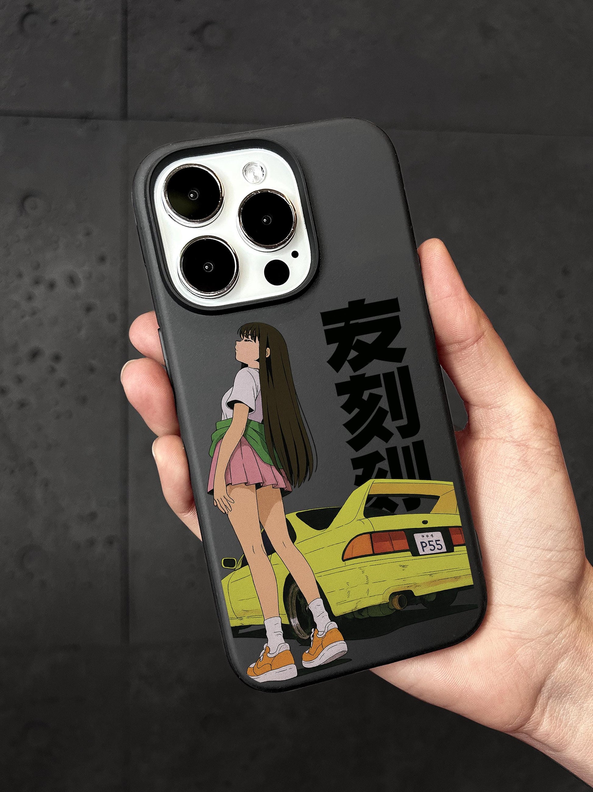 A person&#39;s hand holding a phone case with an illustration of a girl and a yellow car.