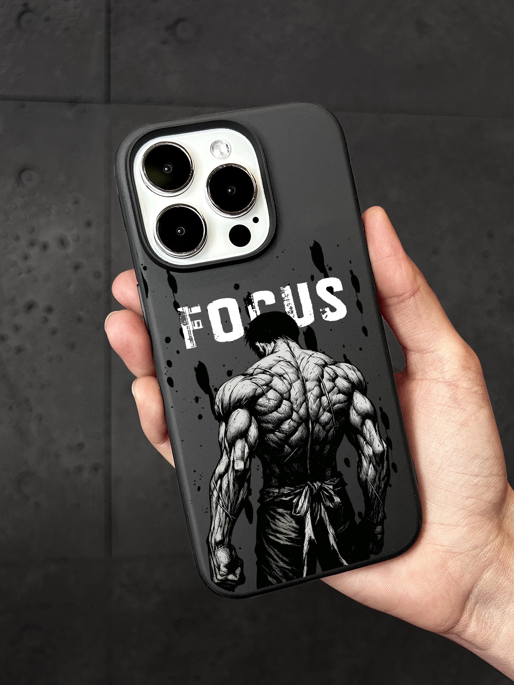 A person&#39;s hand holding a phone case with a muscular man&#39;s back facing the camera, and the word &quot;FOCUS&quot; written on the case.