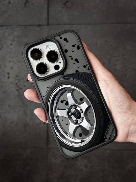 A person&#39;s hand holding a phone case with a design of a car wheel and tire printed on it.