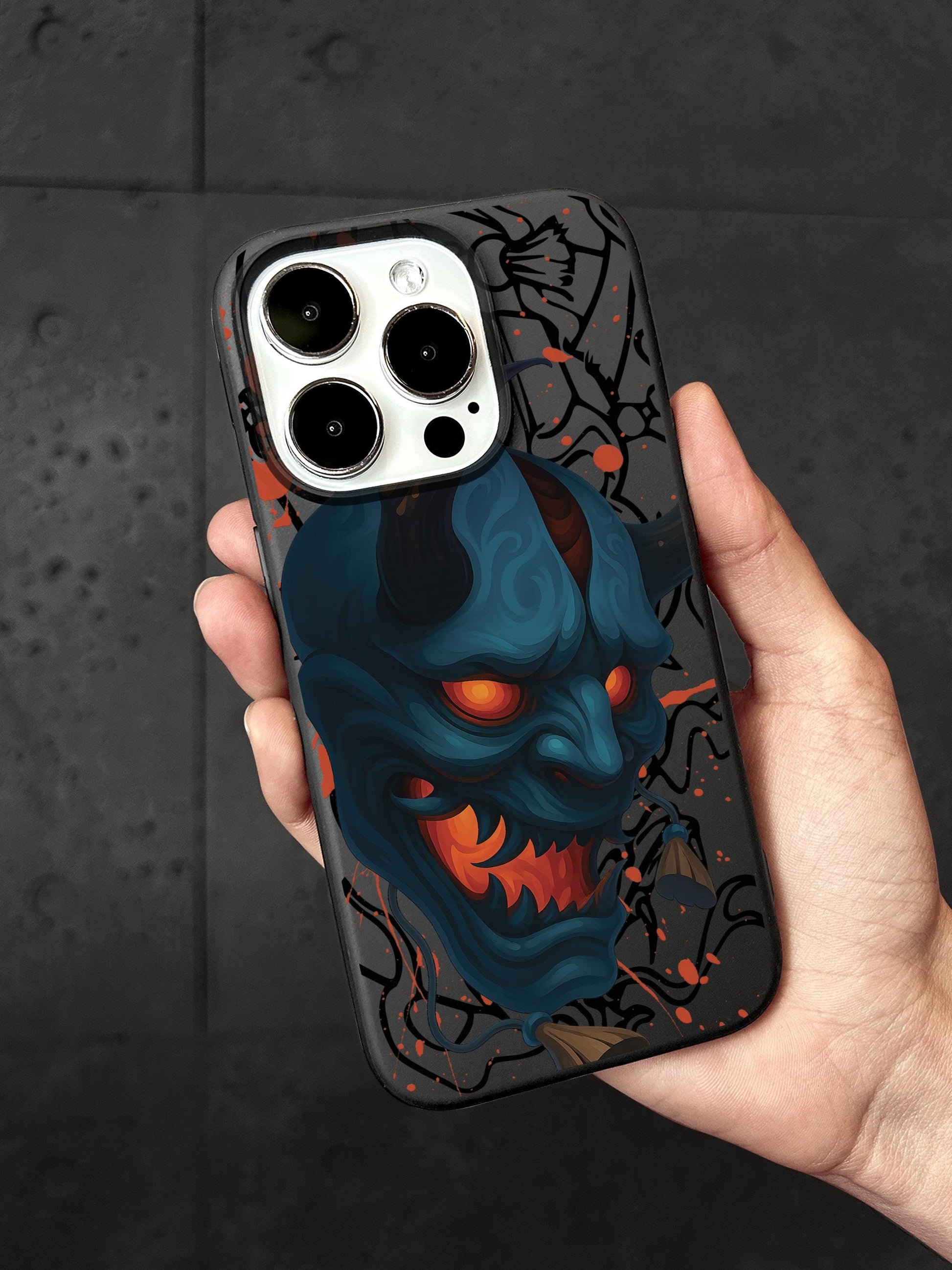 A person&#39;s hand holding a phone case with a graphic design featuring a blue devil-like creature with horns and a red mouth.
