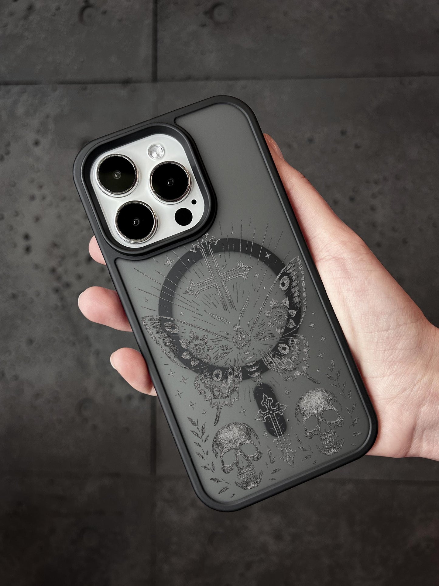 a person holding a black phone case with skulls on it