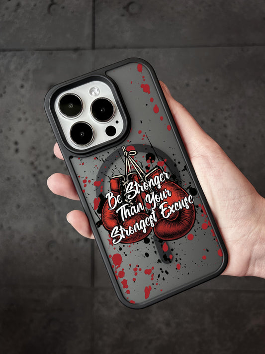A person&#39;s hand holding a phone case with a design featuring boxing gloves and the text &quot;Be Stronger Than Your Strongest Exercise&quot;.