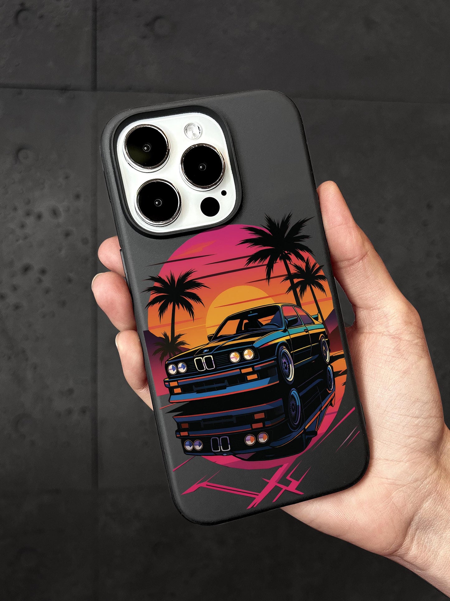 A person&#39;s hand holding a phone case with a colorful graphic of a car and palm trees on it.