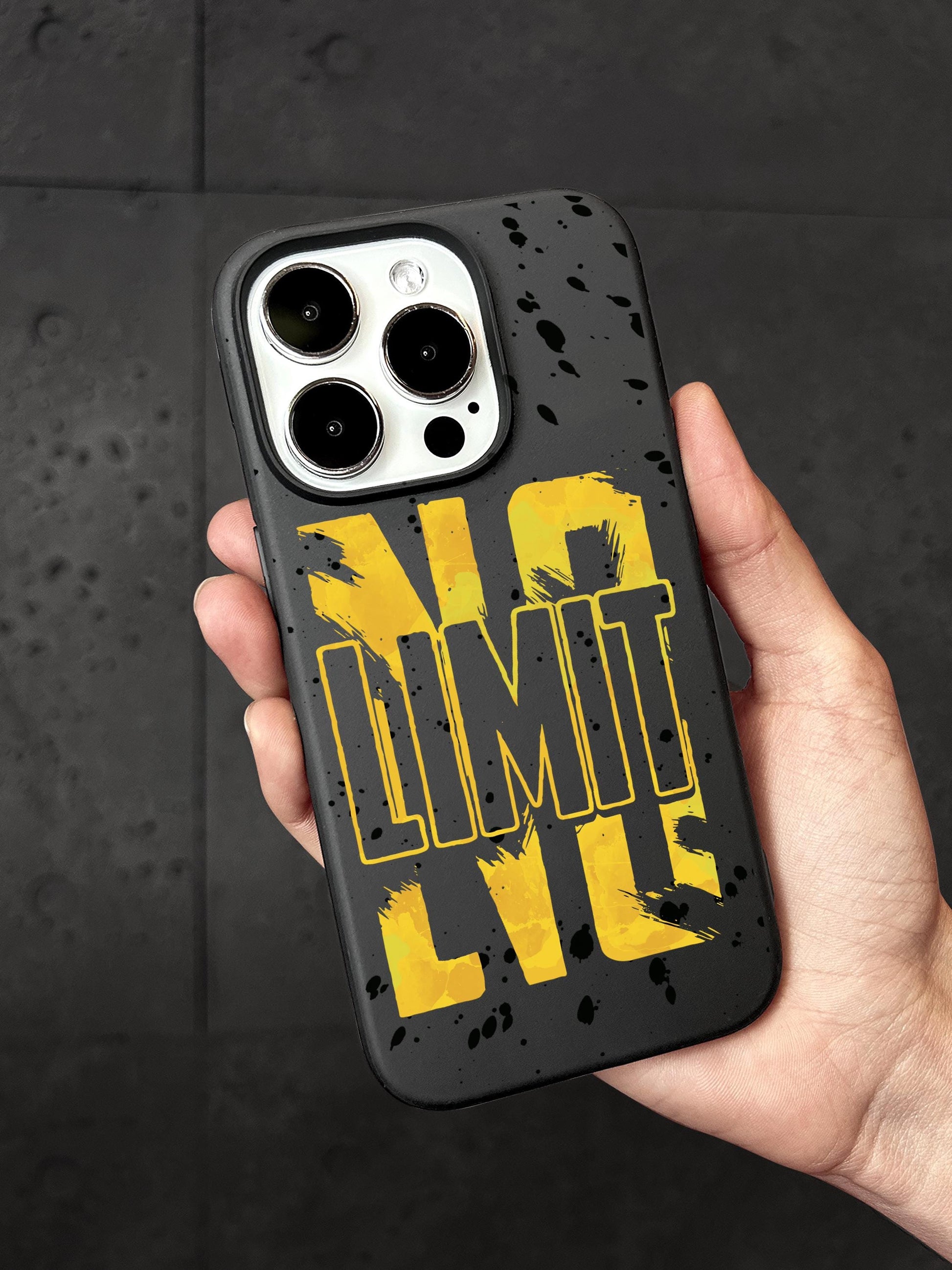 A person&#39;s hand holding a black phone case with a yellow and black design featuring the word &quot;LIMIT&quot; in large letters.