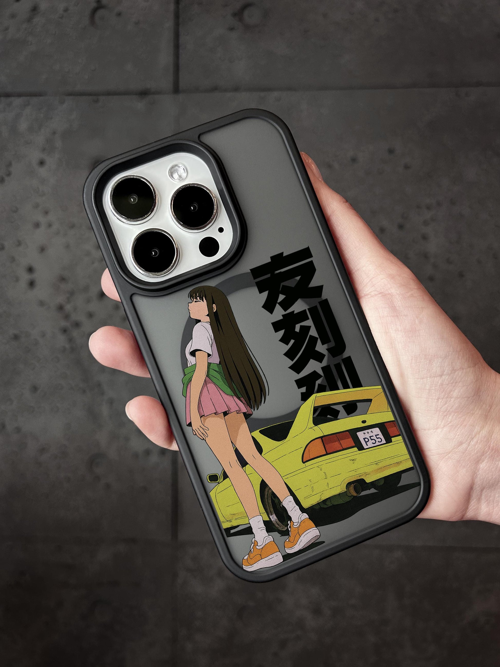 A person holding a phone case with an anime-style illustration of a girl and a yellow car.