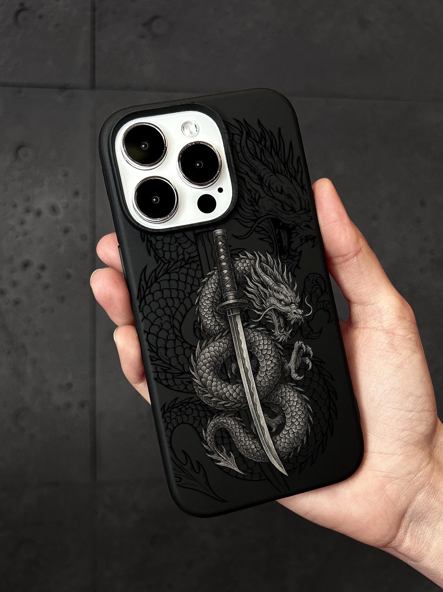a hand holding a black phone case with a dragon on it