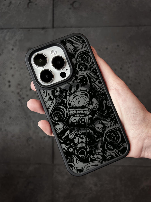 A hand holding a black phone case with a detailed black and white pattern of various mechanical and industrial elements.