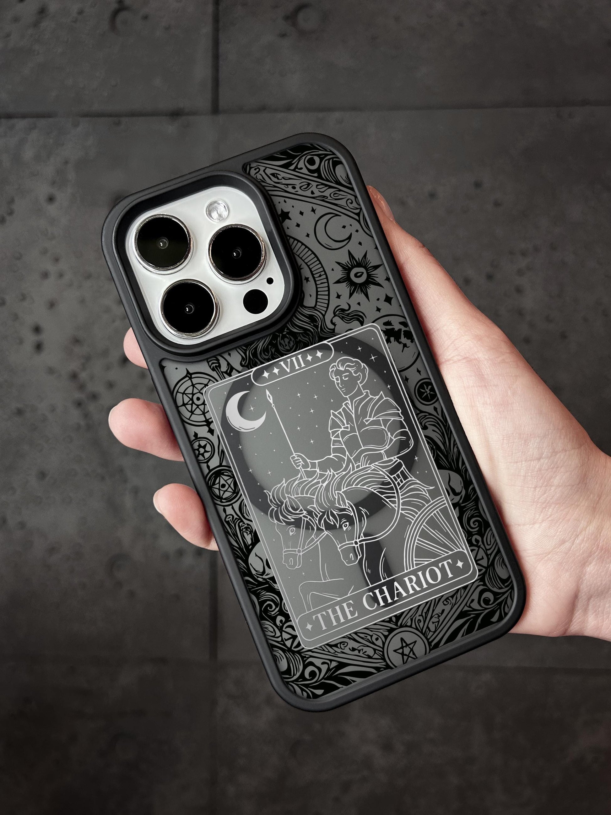 A hand holding a phone case with a detailed design featuring a tarot card image.