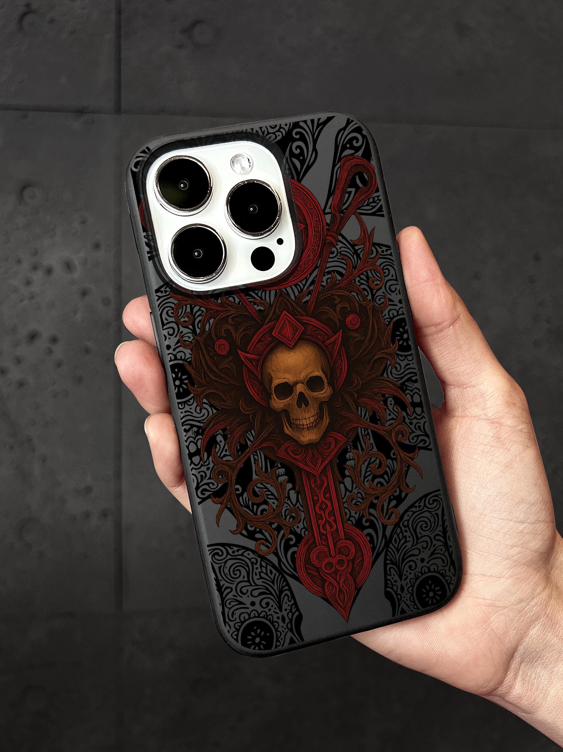a hand holding a phone case with a skull on it