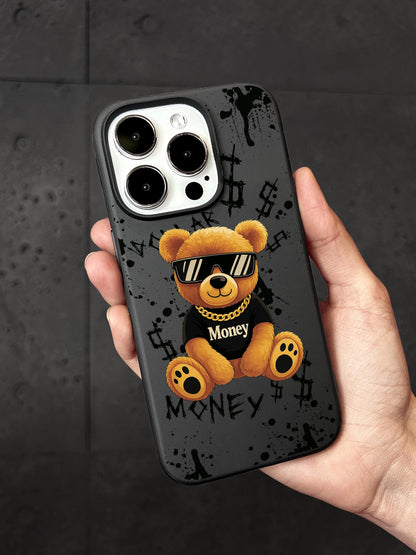 A person&#39;s hand holding a phone case featuring a teddy bear wearing sunglasses and a black shirt with the word &quot;Money&quot; written on it.