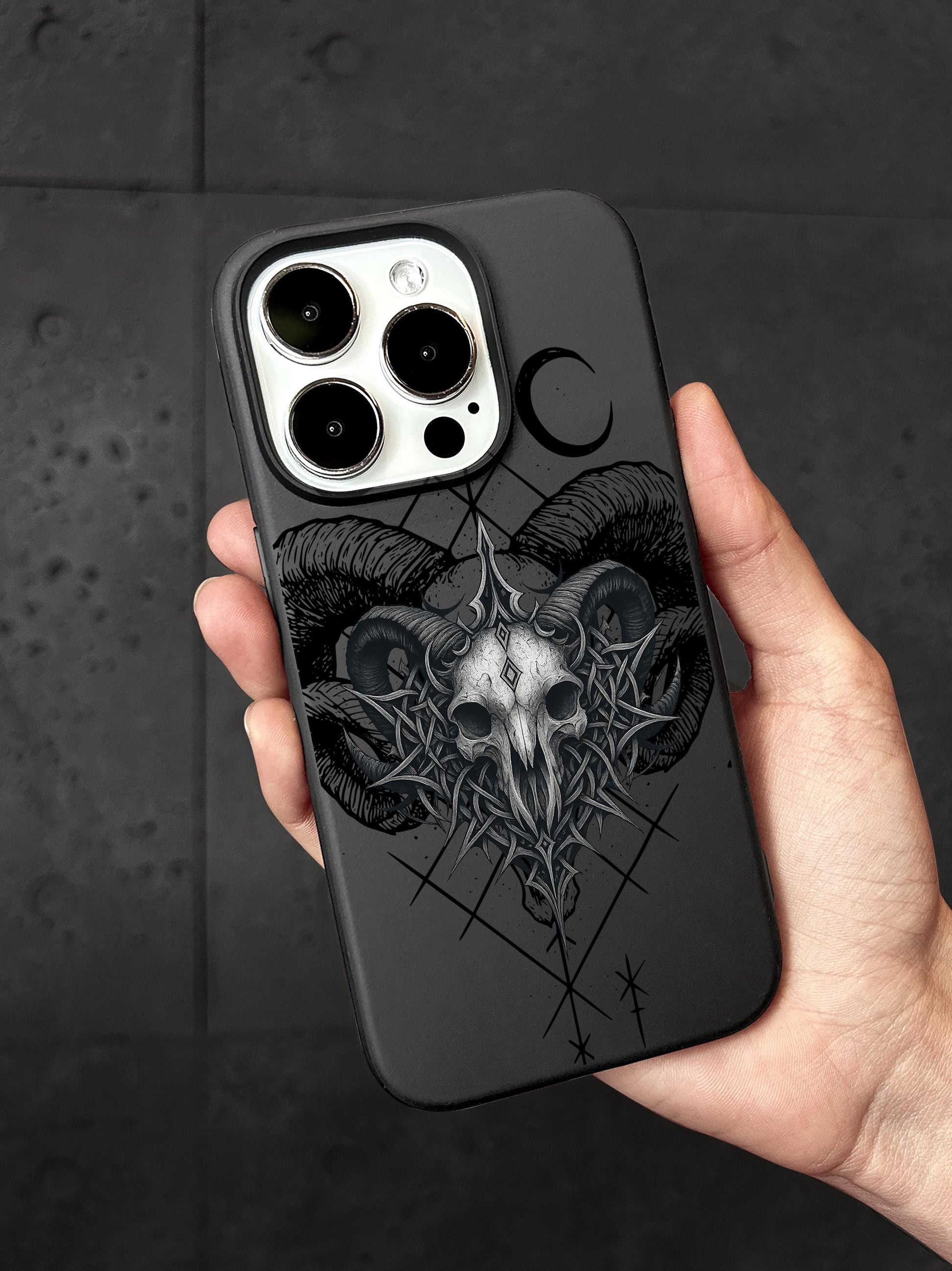 a person holding a black phone case with a goat skull on it