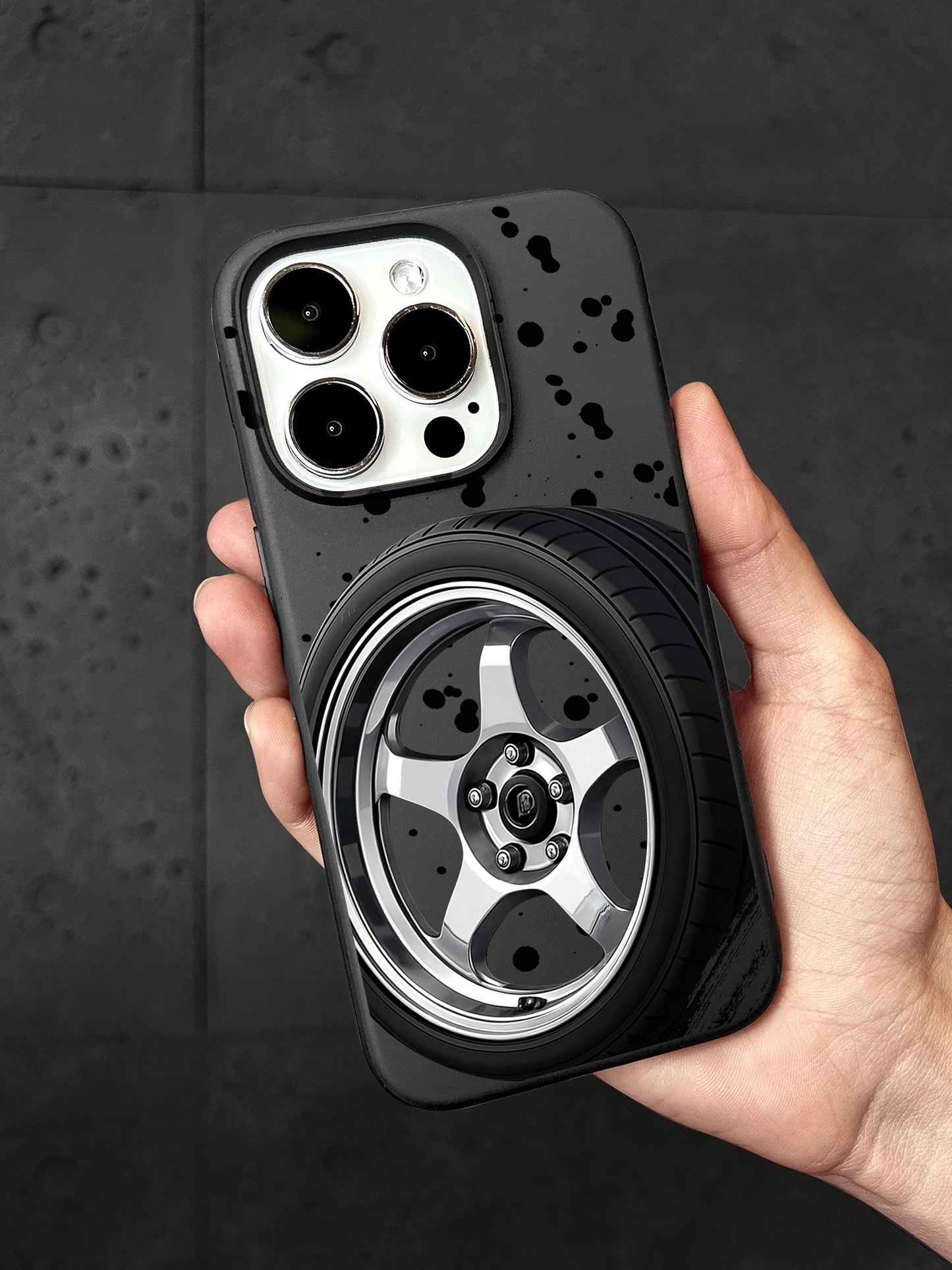A person&#39;s hand holding a phone case with a car wheel design on it.