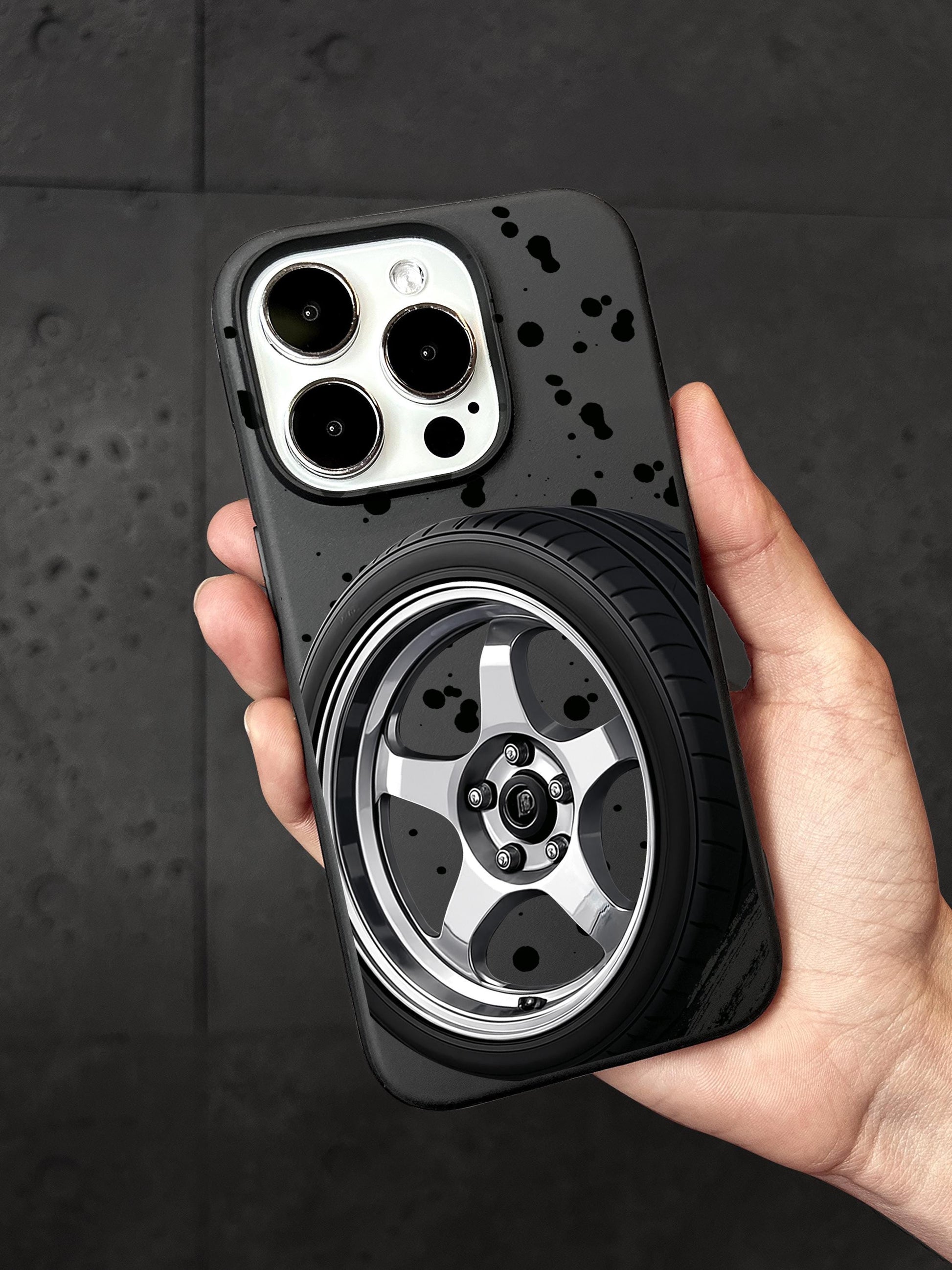 A person&#39;s hand holding a phone case with a car wheel design on it.